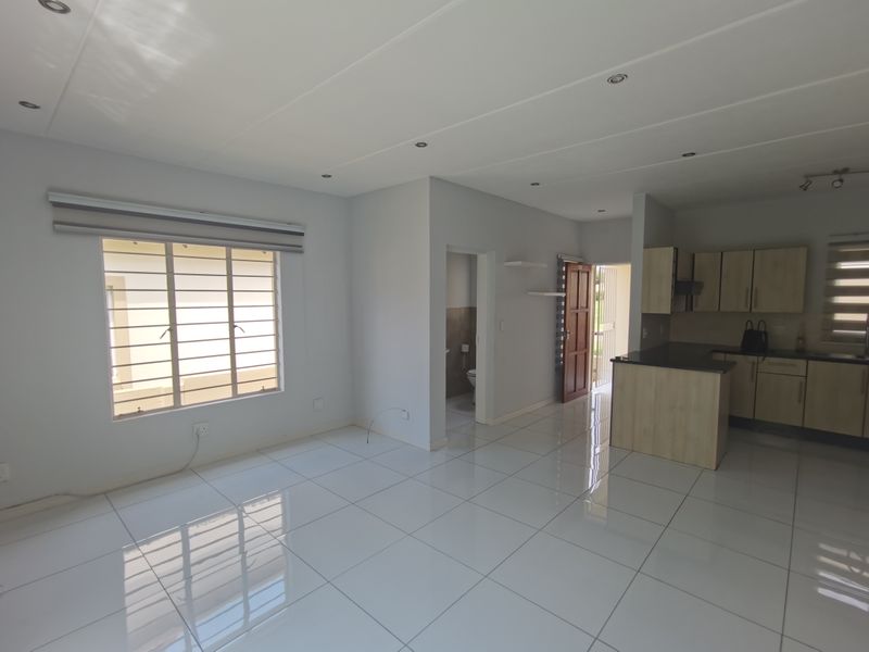 Spacious open-plan living and kitchen area featuring modern porcelain floor tiles, recessed lighting, and a functional kitchen with granite countertops.