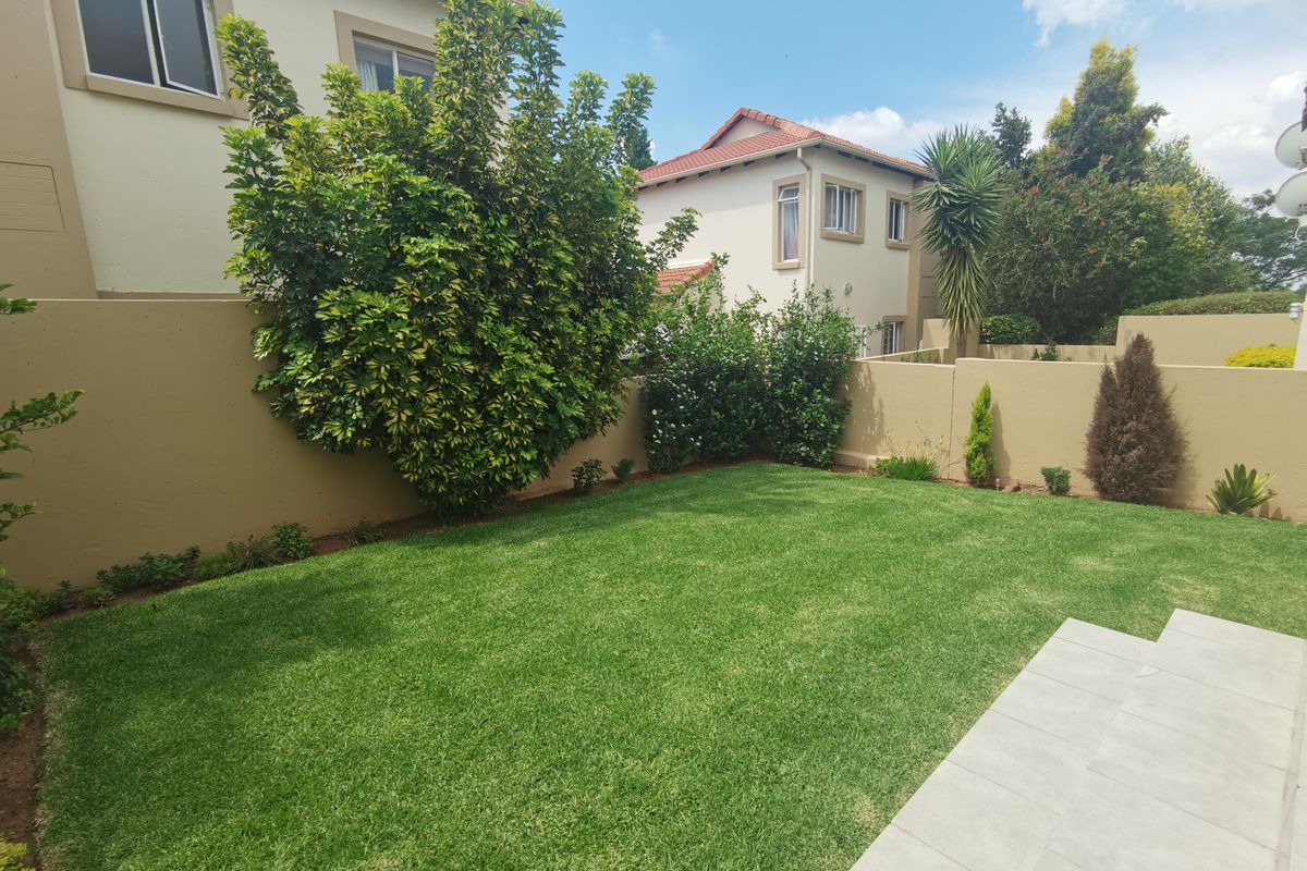A well-maintained private rear garden featuring a manicured lawn, boundary walls, and a paved patio area, providing a pleasant outdoor space.