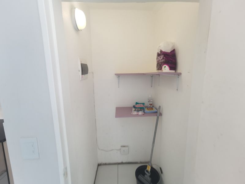 A small utility or storage closet featuring wall-mounted shelving, an electrical distribution board, and basic lighting, suitable for organized storage.