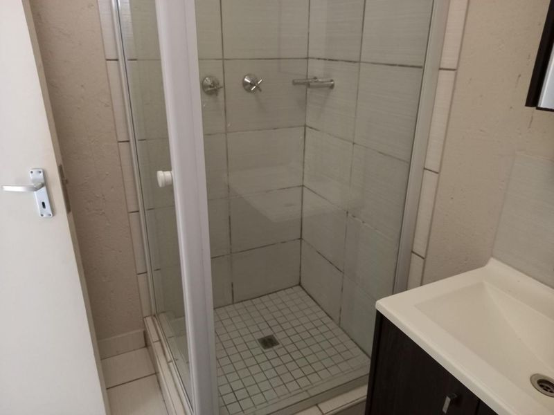 A functional bathroom featuring a glass shower enclosure, tiled finishes, and a modern vanity cabinet with an integrated basin.