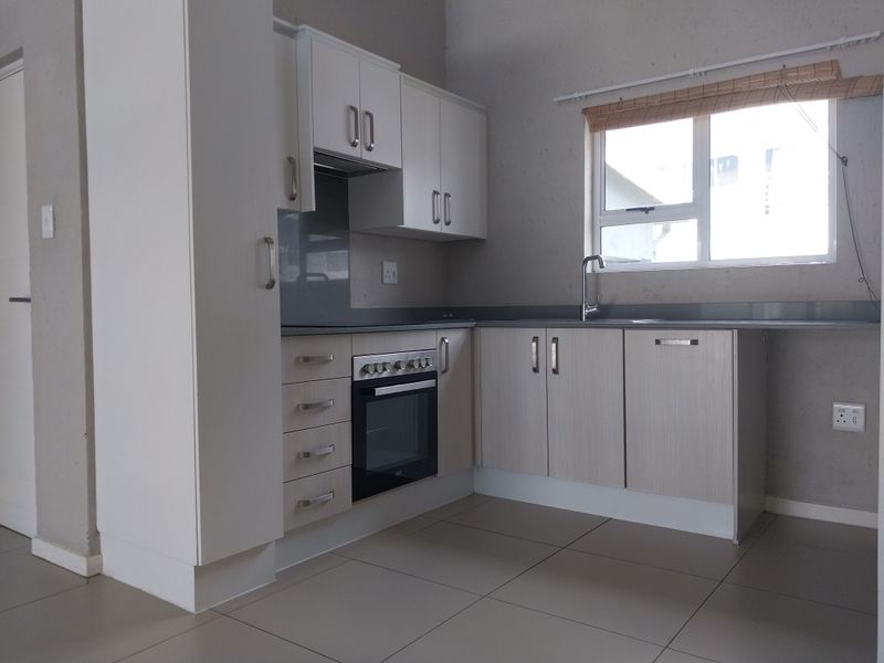 A clean, functional kitchen featuring light-toned cabinetry, built-in oven, hob, and tiled flooring, offering a neutral space ready for personalization.