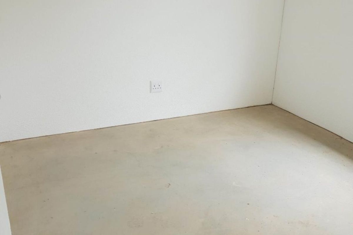 An empty, unfinished room featuring plain white walls and exposed concrete flooring, suitable for customization or flooring installation.