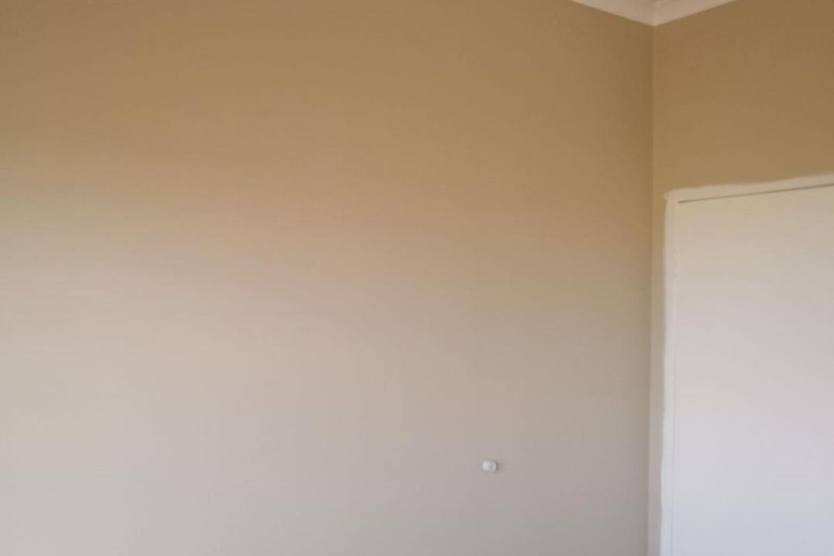 A simple interior view of a room featuring neutral painted walls and a white door frame.