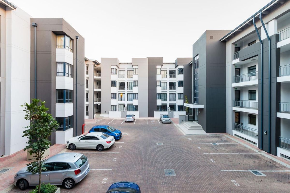 A view of the apartment complex courtyard featuring paved parking bays and modern multi-story building facades with balconies.