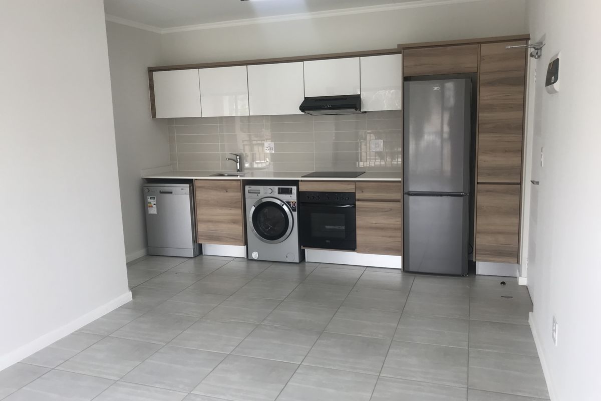 Modern kitchen featuring sleek two-tone cabinetry, tiled backsplash, integrated oven, hob, extractor fan, and tiled flooring in an open-plan layout.