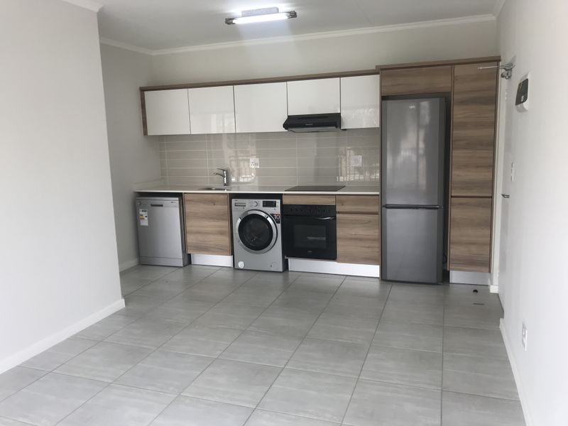 Modern kitchen featuring sleek two-tone cabinetry, tiled backsplash, integrated oven, hob, extractor fan, and tiled flooring in an open-plan layout.
