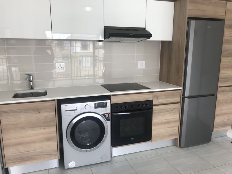Modern kitchen featuring sleek white and wood-grain cabinetry, stone countertops, integrated appliances, and a tiled backsplash in a clean, contemporary finish.