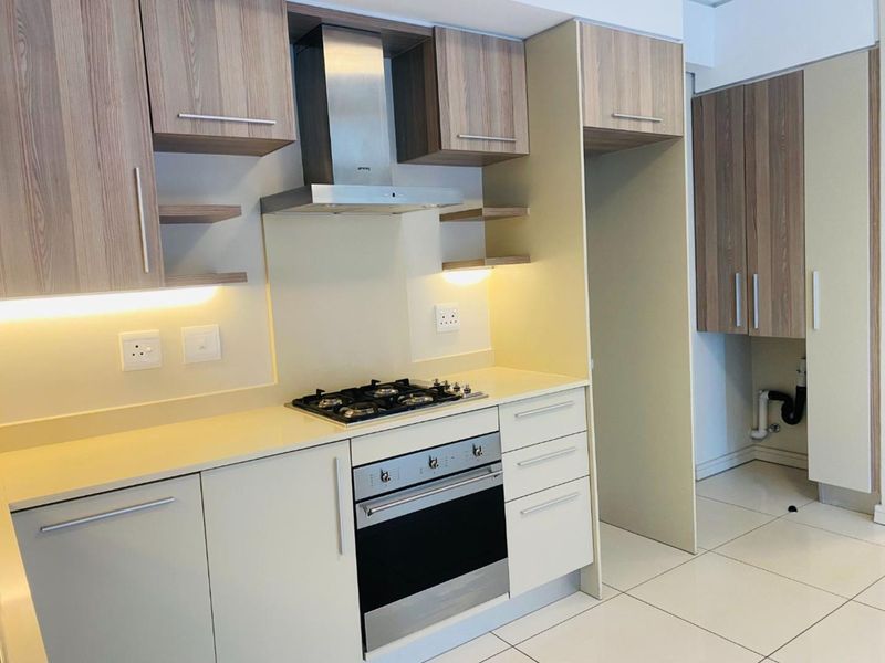Modern kitchen featuring light-toned cabinetry, built-in gas hob, stainless steel oven, extractor fan, and tiled flooring with ample storage space.
