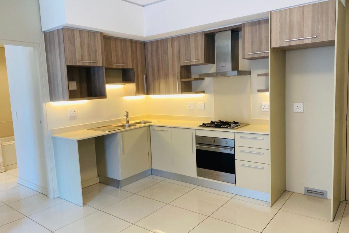 Modern kitchen featuring light-toned cabinetry, integrated stainless steel appliances, gas hob, extractor fan, and tiled flooring with under-cabinet lighting.