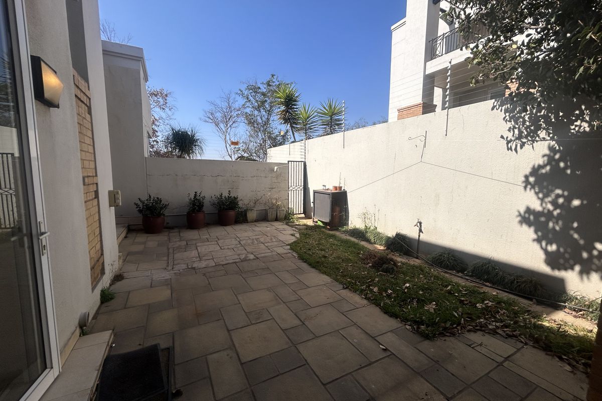 A private rear courtyard featuring paved flooring, a small grass section, and high boundary walls, providing a secure outdoor space.