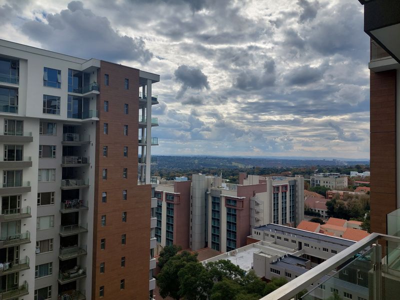 Elevated urban view overlooking surrounding apartment complexes and distant landscape under a cloudy sky.