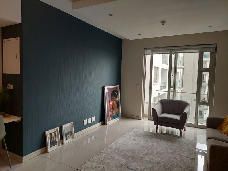 A modern living room featuring a dark blue accent wall, tiled flooring, and large sliding glass doors leading to a balcony.