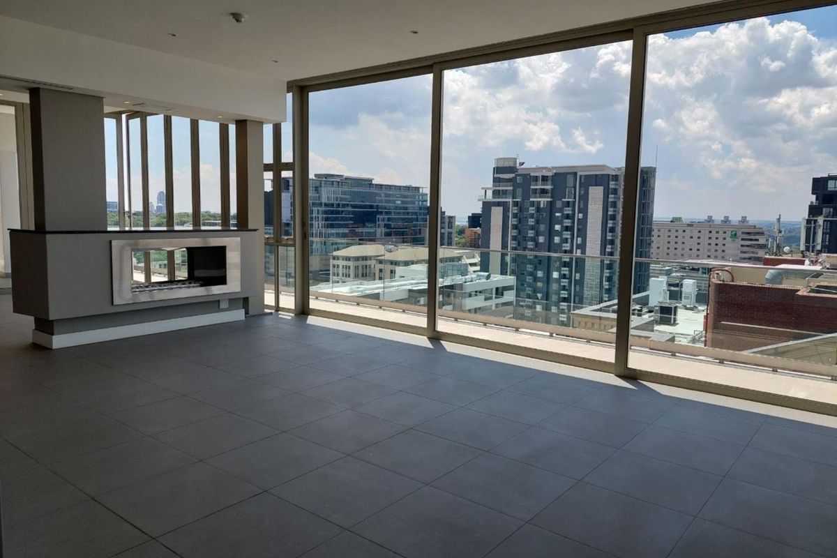 Spacious open-plan living area featuring large floor-to-ceiling windows, a modern built-in fireplace, and expansive city views.