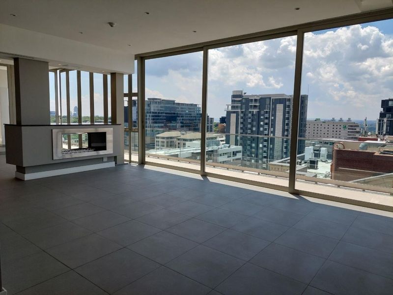Spacious open-plan living area featuring large floor-to-ceiling windows, a modern built-in fireplace, and expansive city views.