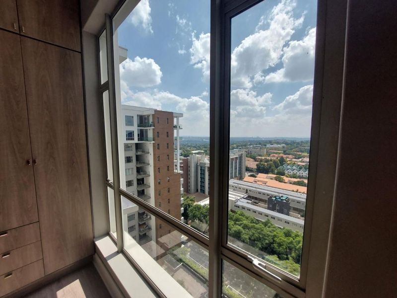 A bright interior space featuring floor-to-ceiling windows with expansive urban views and integrated built-in cabinetry.