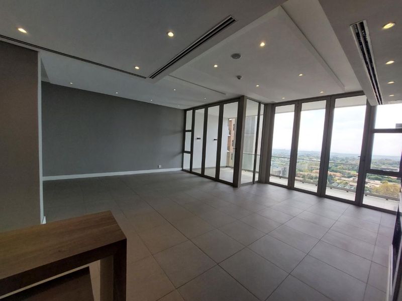 Spacious, modern open-plan living area featuring large glass sliding doors, recessed lighting, ducted air conditioning, and neutral tiled flooring with expansive views.
