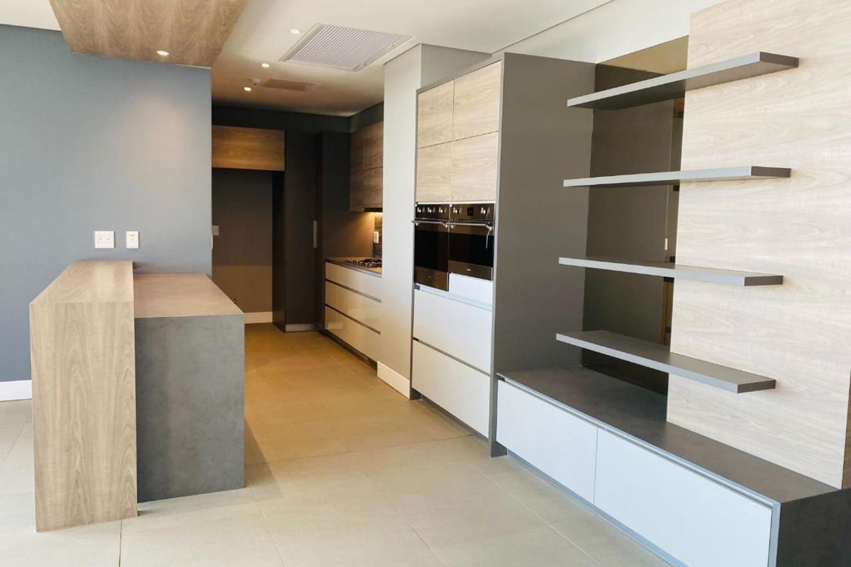 Modern, high-end kitchen featuring sleek built-in cabinetry, a double wall oven, integrated cooktop, and a functional kitchen island with contemporary finishes.