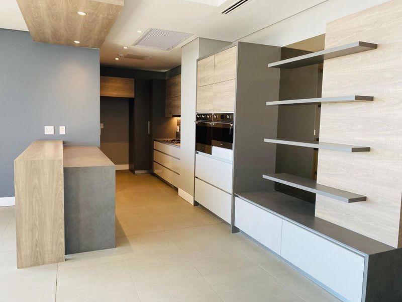Modern, high-end kitchen featuring sleek built-in cabinetry, a double wall oven, integrated cooktop, and a functional kitchen island with contemporary finishes.