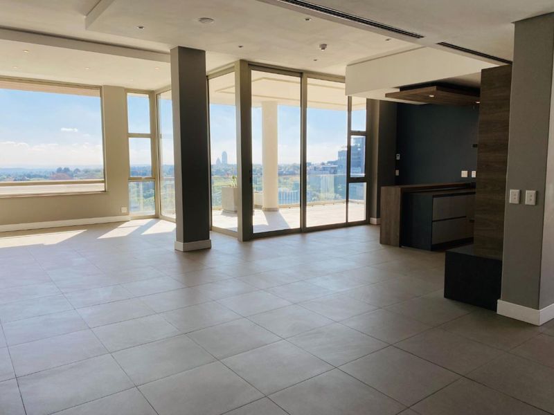 Spacious open-plan living area featuring modern tiled floors, recessed lighting, and large sliding glass doors leading to a balcony with expansive city views.