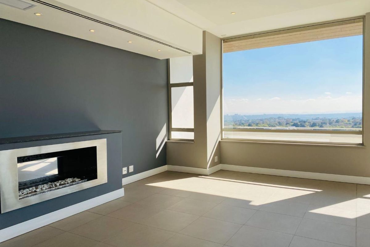 Spacious, modern living area featuring a sleek built-in fireplace, large windows with expansive views, and neutral tiled flooring.