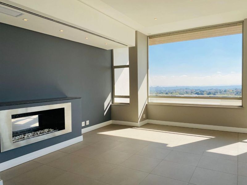 Spacious, modern living area featuring a sleek built-in fireplace, large windows with expansive views, and neutral tiled flooring.
