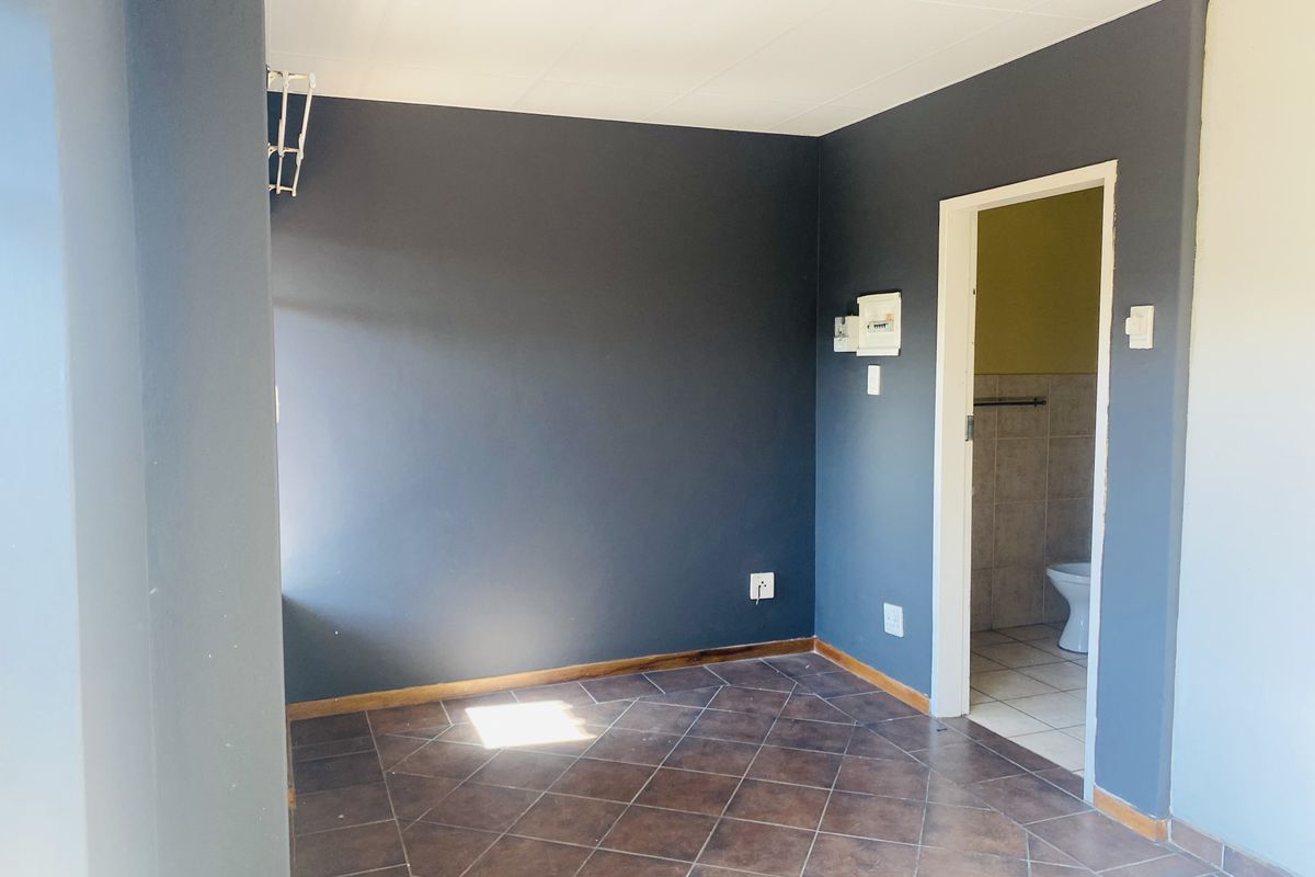 An empty bedroom featuring dark painted walls, tiled flooring, and direct access to an adjoining bathroom.