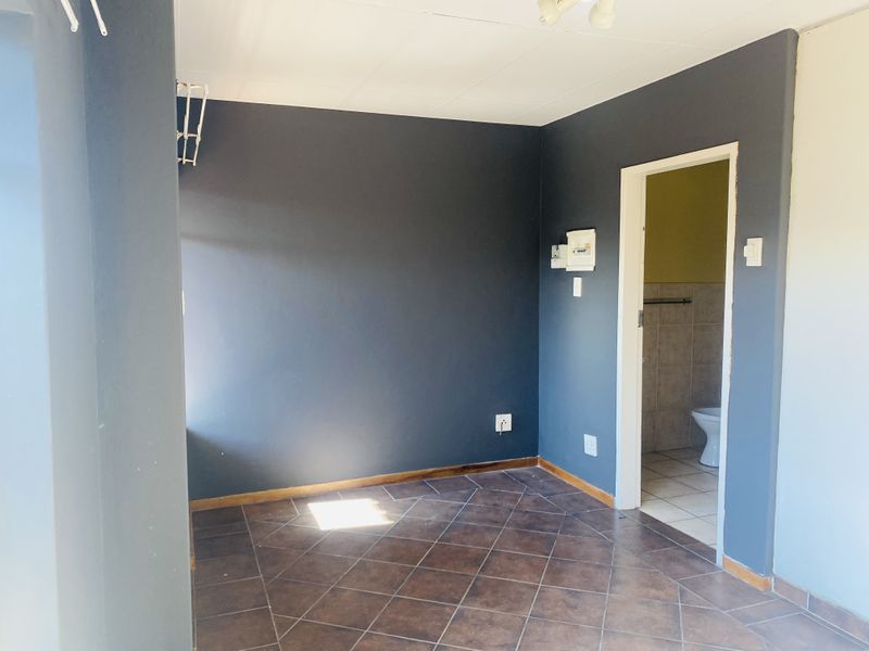 An empty bedroom featuring dark painted walls, tiled flooring, and direct access to an adjoining bathroom.