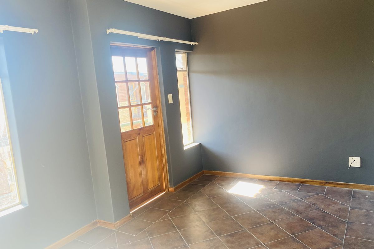 An empty living room featuring dark grey walls, tiled flooring, and a wooden exterior door with glass panes.