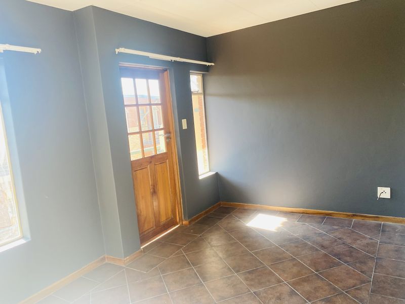 An empty living room featuring dark grey walls, tiled flooring, and a wooden exterior door with glass panes.