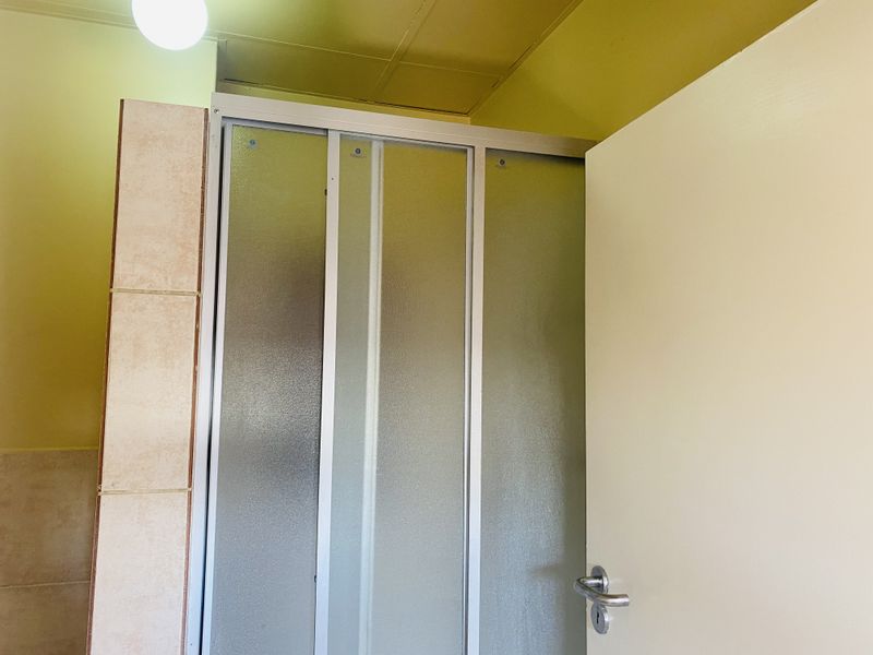 A bathroom featuring a shower enclosure with frosted glass doors and tiled wall finishes.