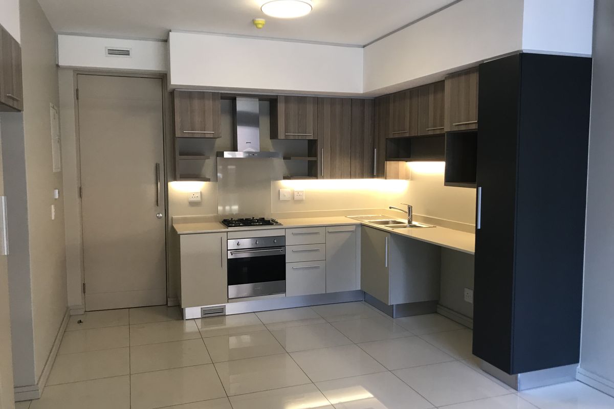 Modern kitchen featuring built-in cabinetry, gas hob, electric oven, extractor fan, and tiled flooring in a clean, contemporary layout.