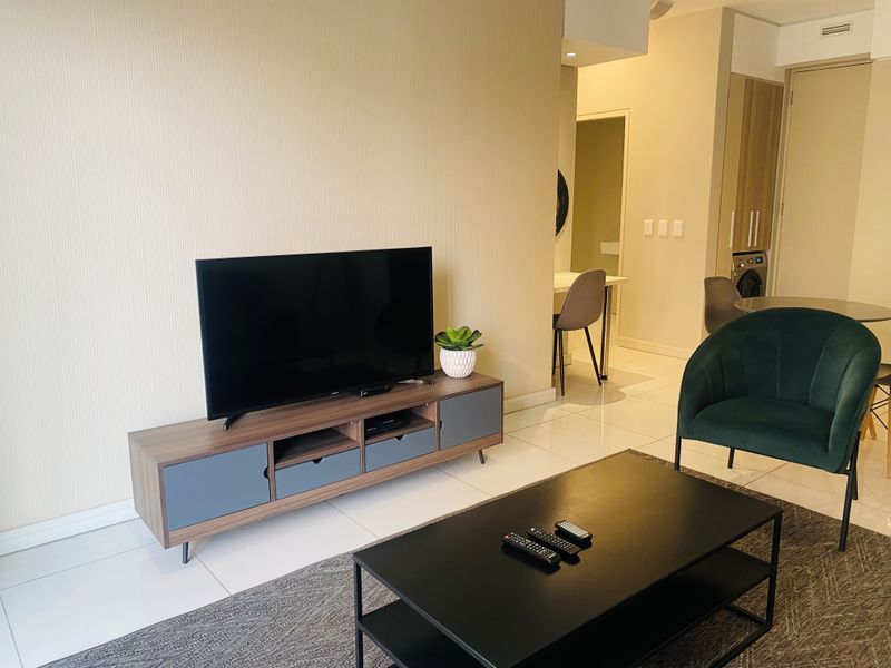 Modern open-plan living area featuring sleek tiled flooring, neutral wall finishes, and integrated cabinetry, creating a bright and functional living space.