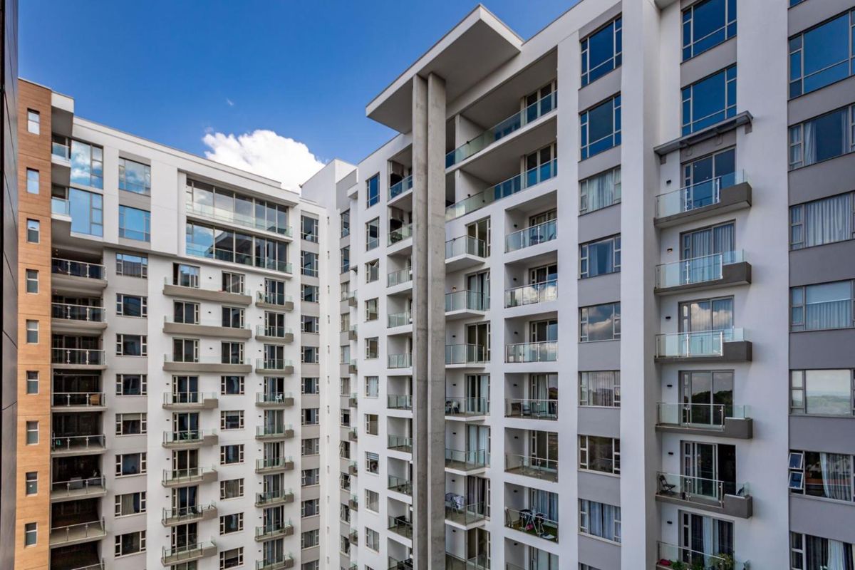 A modern high-rise apartment building exterior featuring multiple levels of balconies with glass balustrades and contemporary architectural design.
