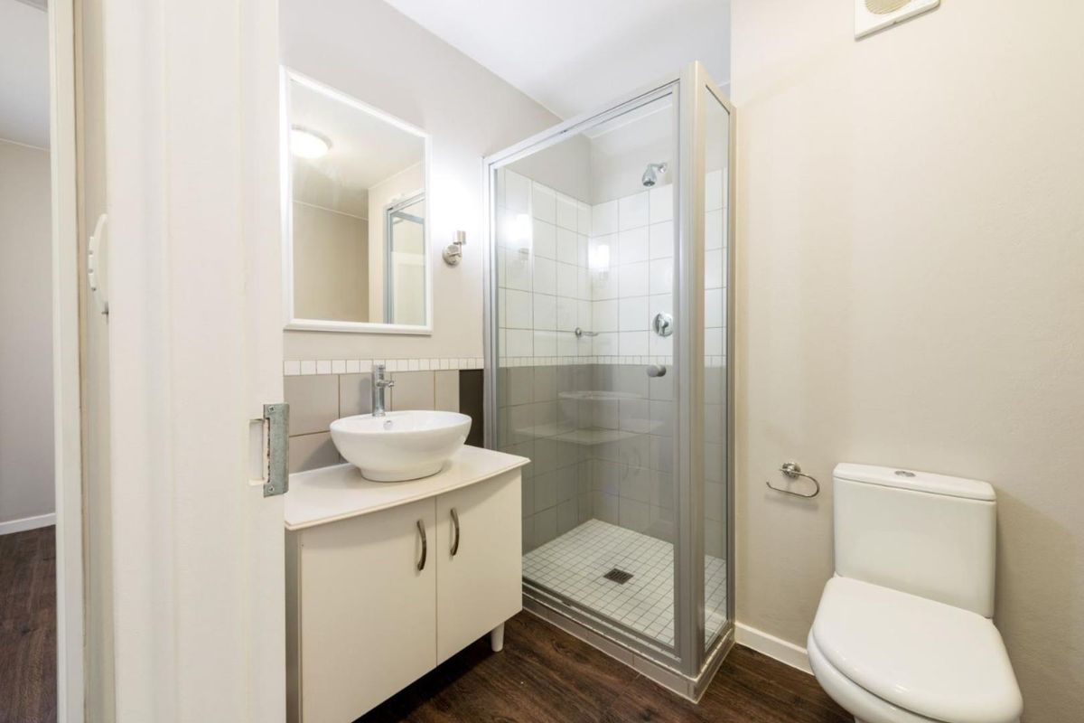 A clean and functional bathroom featuring a glass-enclosed shower, a modern vessel sink vanity, and a standard toilet.