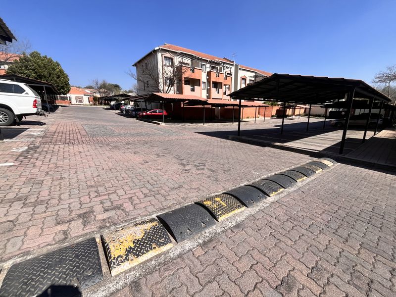 Exterior view of the apartment complex parking area featuring paved driveways and covered carport structures.