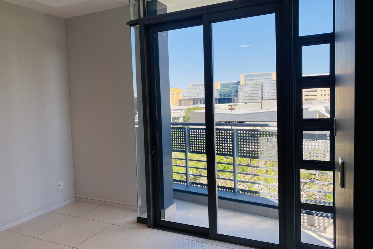 Bright and modern living area featuring large sliding glass doors that open onto a private balcony with urban views.
