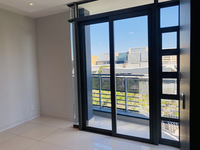 Bright and modern living area featuring large sliding glass doors that open onto a private balcony with urban views.