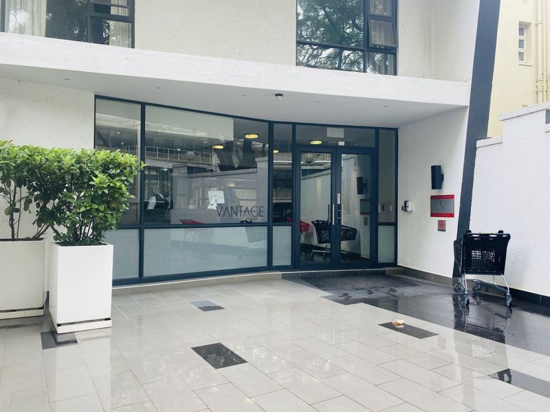 Modern apartment building entrance featuring a glass facade, aluminum-framed glass doors, and a clean, tiled entrance area.