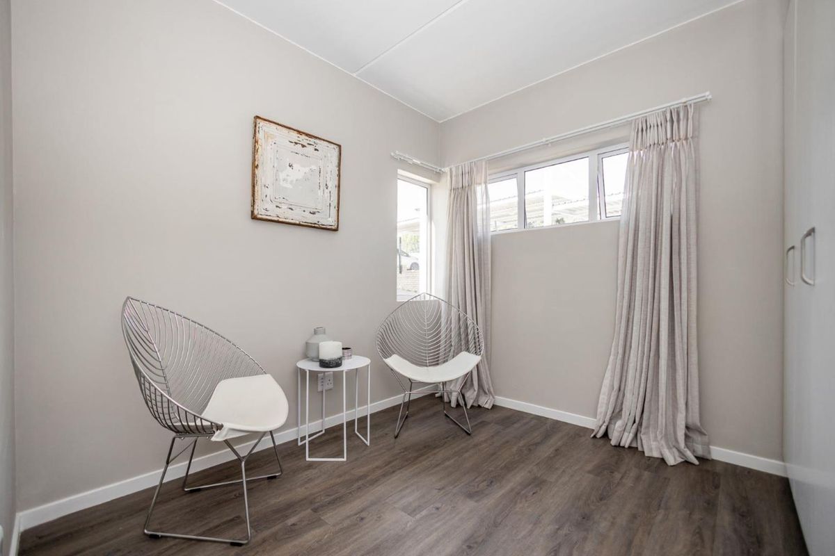 A bright bedroom featuring modern laminate flooring, neutral wall tones, and a built-in wardrobe, offering a clean and contemporary living space.