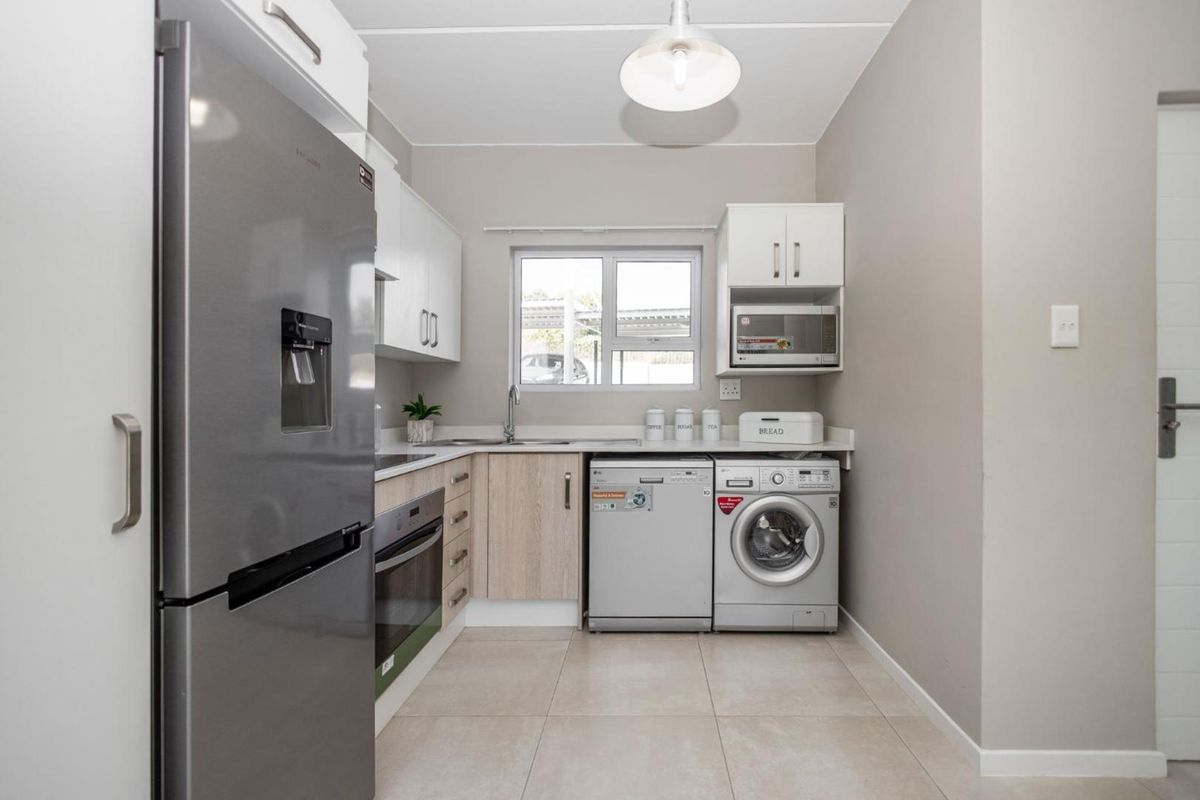 A well-maintained kitchen featuring modern cabinetry, tiled flooring, built-in oven, and integrated appliance spaces, offering a clean and functional culinary environment.