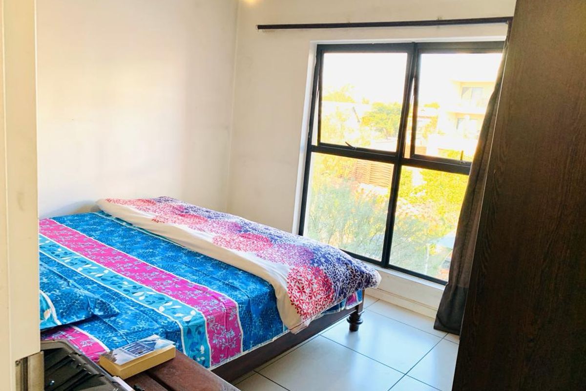A bright bedroom featuring tiled flooring and a large window that allows for ample natural light.