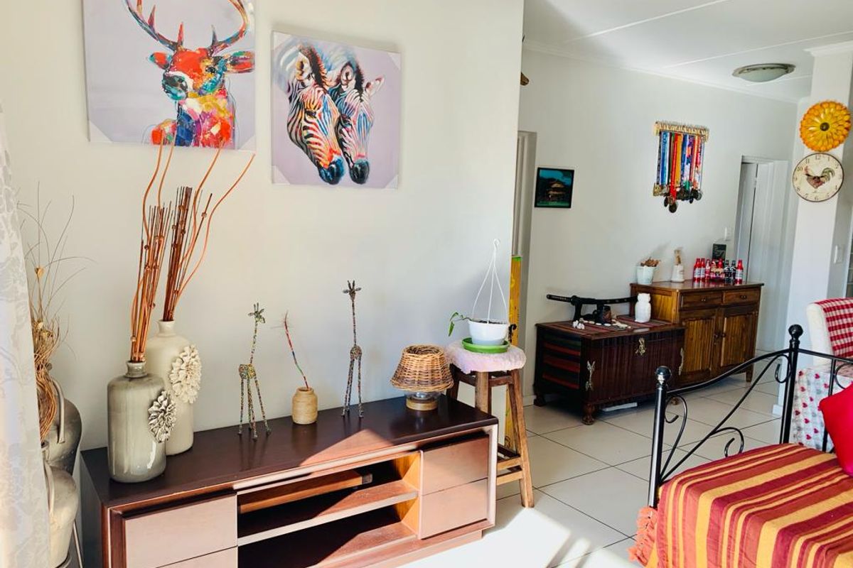 A living area featuring neutral walls and tiled flooring, providing a functional space with access to adjacent rooms.