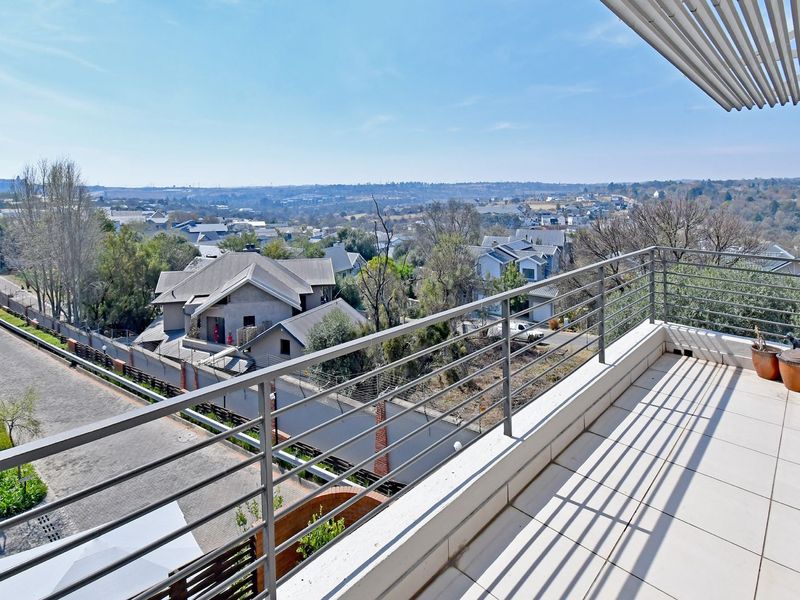A spacious balcony featuring tiled flooring, a modern metal balustrade, and a louvred roof, offering expansive elevated views of the surrounding neighbourhood.