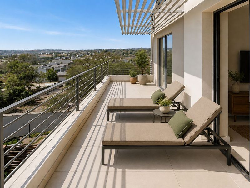 A spacious, modern balcony featuring tiled flooring, a metal balustrade, and an overhead pergola, offering expansive views of the surrounding landscape.