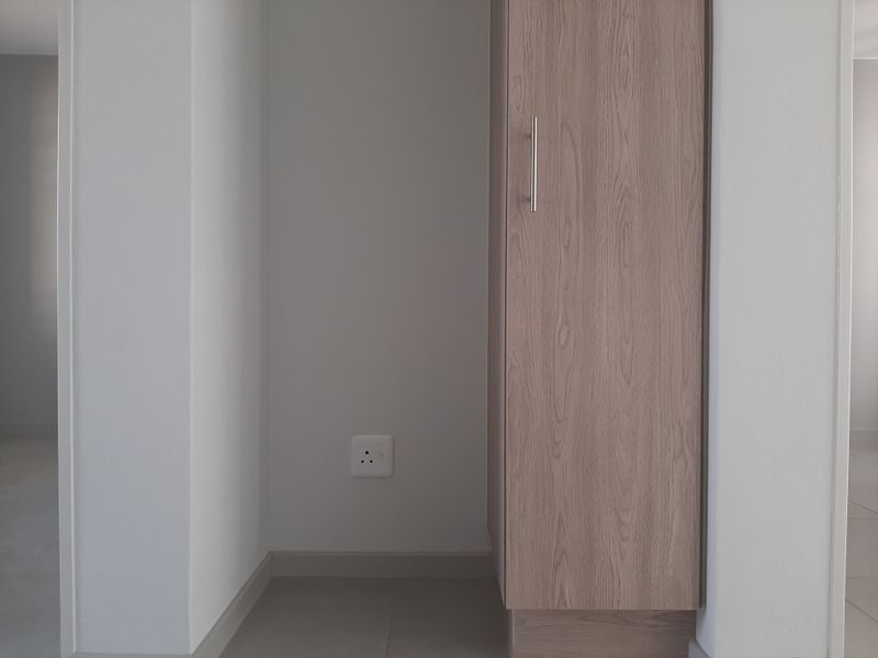 A clean utility space featuring a modern built-in cupboard and an electrical outlet, suitable for storage or appliance placement.