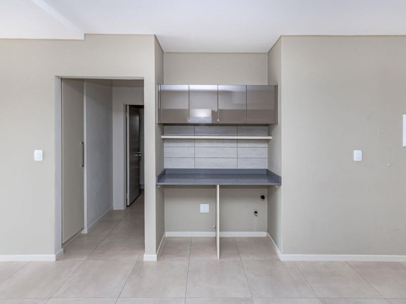 A clean, modern scullery or utility nook featuring built-in cabinetry, stone countertops, and tiled backsplash with dedicated plumbing and electrical connections.