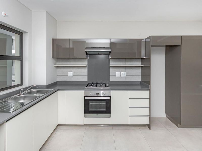 Modern kitchen featuring sleek two-tone cabinetry, stone countertops, built-in gas hob, electric oven, extractor fan, and a double bowl sink.
