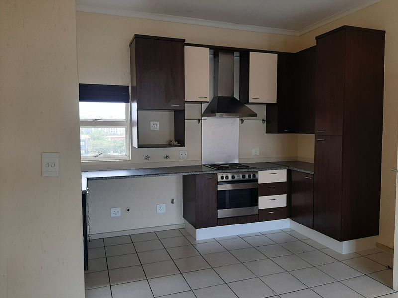 A functional kitchen featuring built-in cabinetry, a stainless steel oven and hob, and tiled flooring, offering a clean and practical layout.