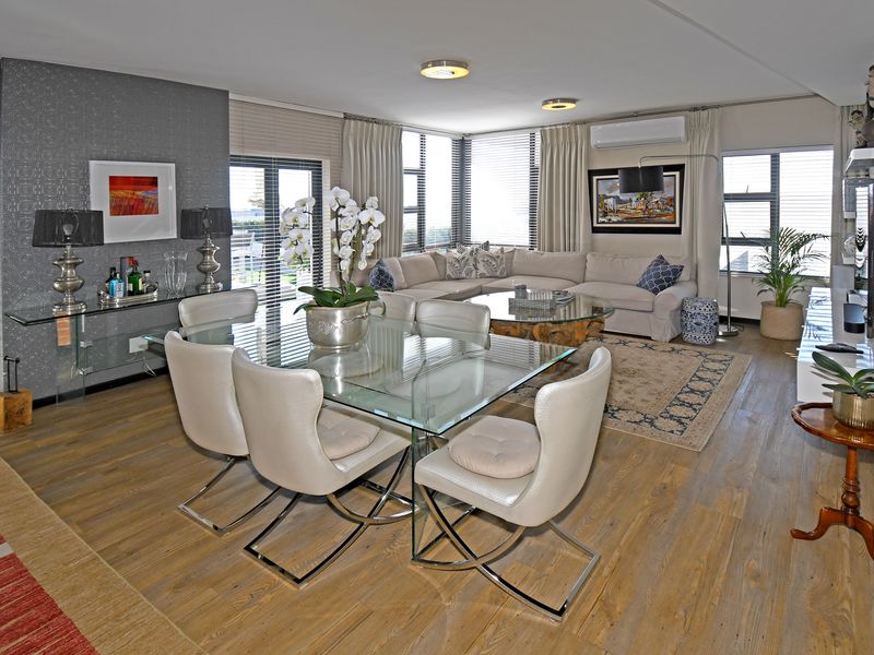 Spacious open-plan living and dining area featuring laminate flooring, split-system air conditioning, and large windows providing ample natural light.
