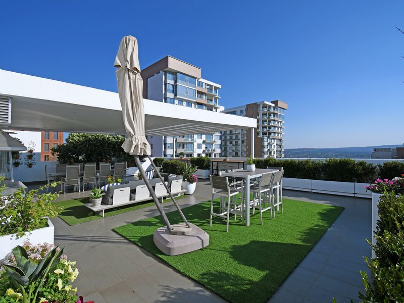 Spacious rooftop terrace featuring a covered patio area, built-in planter boxes, and modern tiled flooring, offering an ideal space for outdoor entertaining.